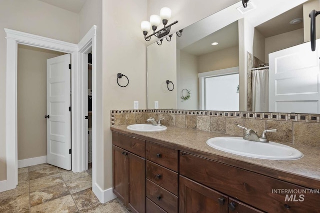 full bath with baseboards, double vanity, and stone finish flooring