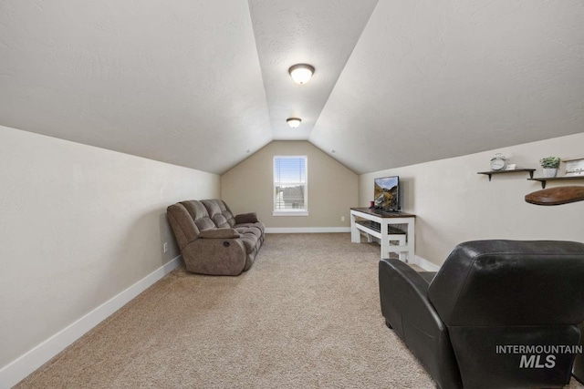 living area featuring vaulted ceiling, carpet, baseboards, and a textured ceiling