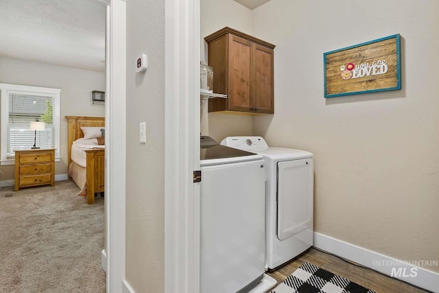 washroom featuring washing machine and dryer, cabinet space, and baseboards