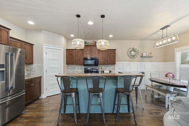 kitchen featuring black appliances, backsplash, dark wood finished floors, a breakfast bar area, and recessed lighting