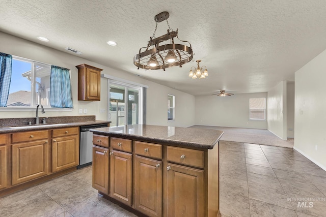kitchen featuring a sink, dishwasher, dark countertops, a chandelier, and plenty of natural light