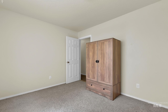 unfurnished bedroom with light colored carpet and baseboards
