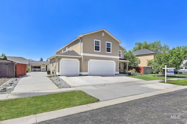 traditional-style home featuring fence, driveway, an attached garage, and stucco siding