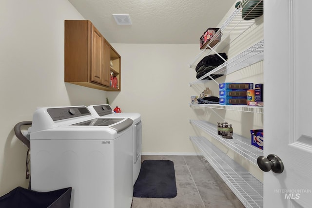 washroom with washer and clothes dryer, cabinet space, a textured ceiling, and baseboards