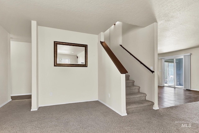 staircase with carpet flooring, a textured ceiling, and baseboards