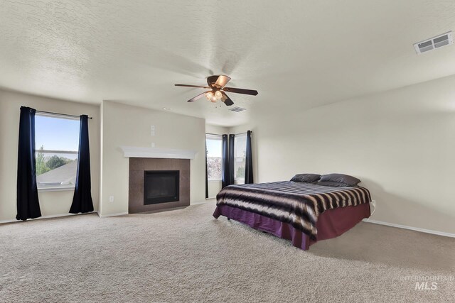 carpeted bedroom with multiple windows, a fireplace, baseboards, and a textured ceiling
