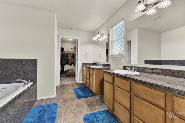 bathroom featuring vanity, a garden tub, a spacious closet, tile patterned floors, and baseboards