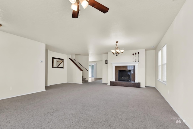 unfurnished living room featuring carpet floors, a chandelier, stairs, and ceiling fan
