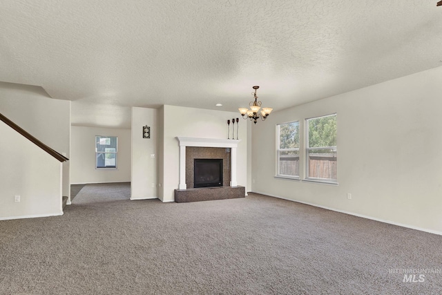 unfurnished living room with a chandelier, carpet, stairs, baseboards, and a textured ceiling