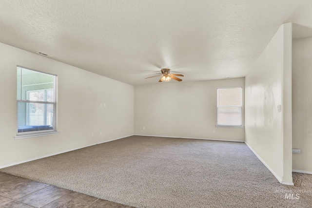 carpeted spare room featuring a ceiling fan, a textured ceiling, and baseboards