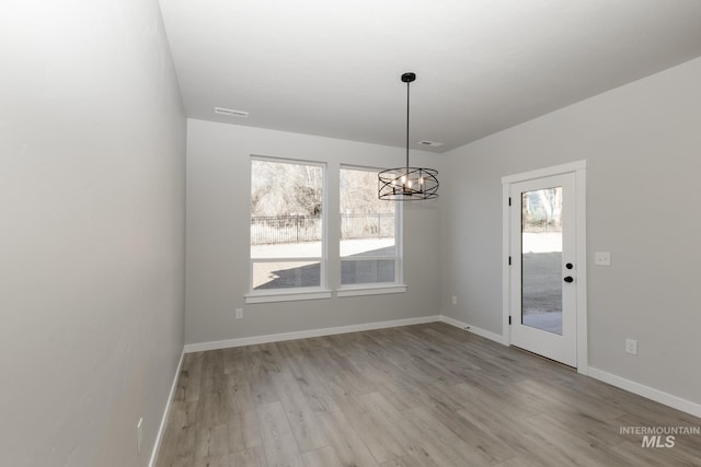 unfurnished dining area with light wood-type flooring, baseboards, visible vents, and a chandelier