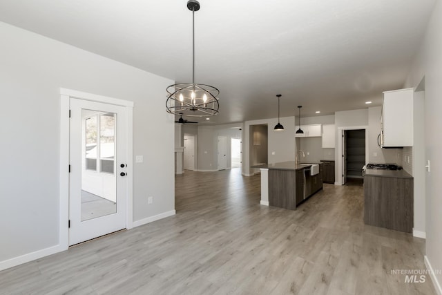 kitchen featuring a sink, open floor plan, white cabinets, and light wood finished floors