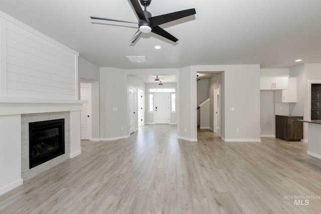 unfurnished living room featuring light wood-style flooring, a fireplace, baseboards, and ceiling fan