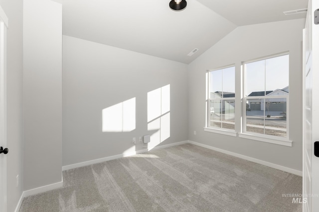 unfurnished room featuring baseboards, lofted ceiling, and light colored carpet