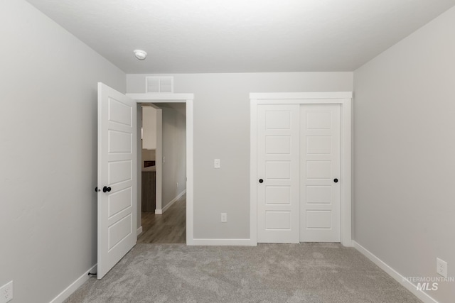 unfurnished bedroom with visible vents, baseboards, carpet, and a closet