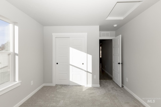 unfurnished bedroom featuring baseboards, light carpet, visible vents, and a closet