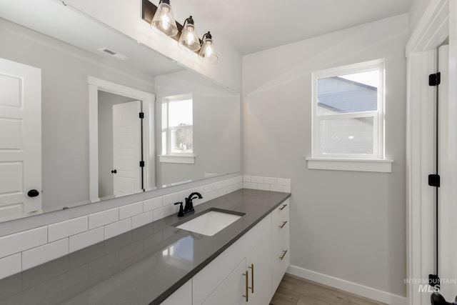 bathroom featuring visible vents, baseboards, wood finished floors, and vanity