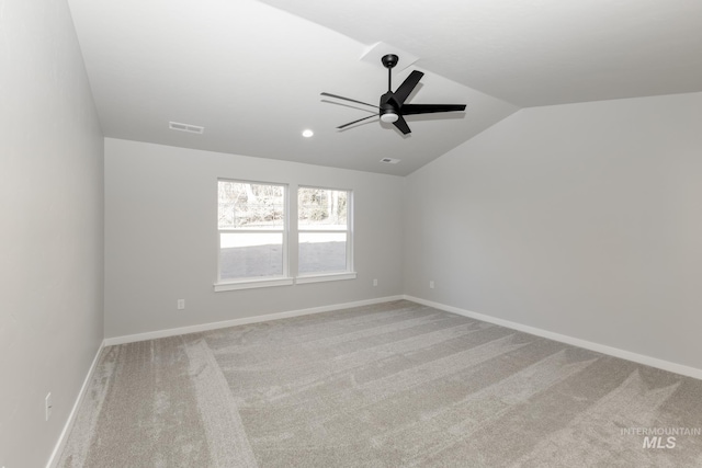 carpeted empty room featuring vaulted ceiling, baseboards, visible vents, and ceiling fan