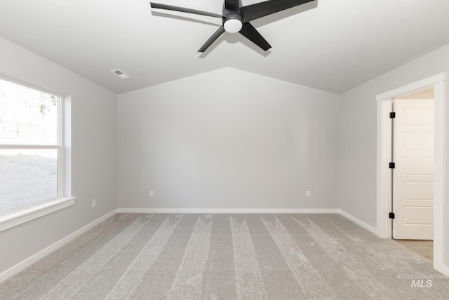 spare room with visible vents, baseboards, lofted ceiling, light carpet, and a ceiling fan