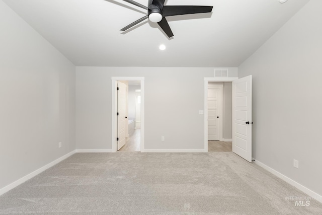 unfurnished bedroom featuring visible vents, ensuite bath, baseboards, light colored carpet, and ceiling fan