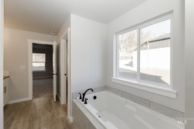 bathroom with visible vents, baseboards, a garden tub, wood finished floors, and vanity