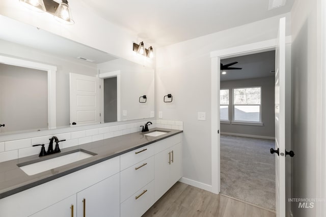 bathroom featuring double vanity, wood finished floors, baseboards, and a sink