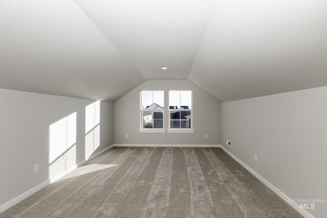 bonus room with baseboards, lofted ceiling, and carpet flooring