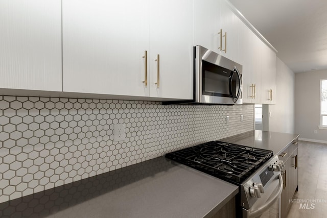 kitchen with dark countertops, decorative backsplash, appliances with stainless steel finishes, and white cabinetry