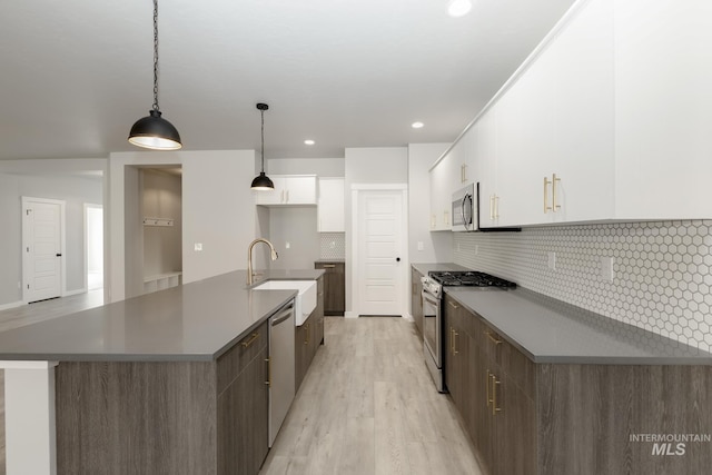 kitchen with light wood-style flooring, appliances with stainless steel finishes, white cabinets, modern cabinets, and a sink