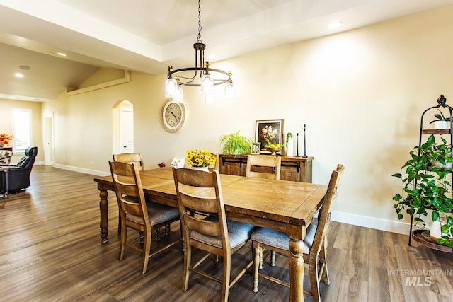 dining space with dark wood-type flooring, vaulted ceiling, and a chandelier