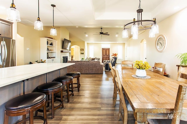 dining room with ceiling fan with notable chandelier and dark hardwood / wood-style flooring