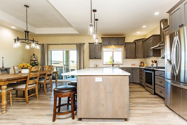 kitchen featuring hanging light fixtures, light wood-type flooring, appliances with stainless steel finishes, and a center island