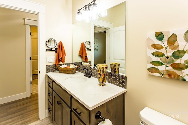 bathroom with vanity, hardwood / wood-style floors, toilet, and decorative backsplash