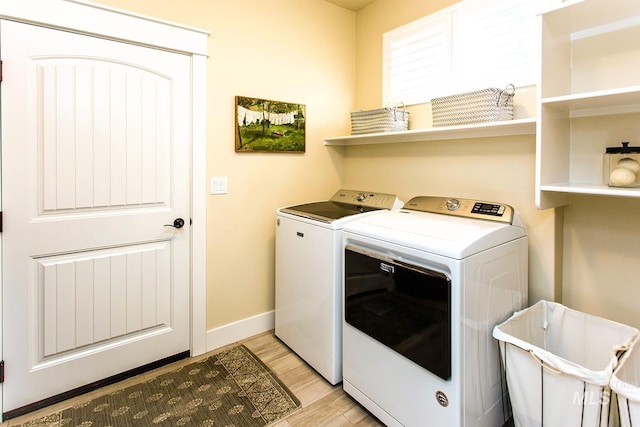 laundry area with light hardwood / wood-style floors and washing machine and clothes dryer