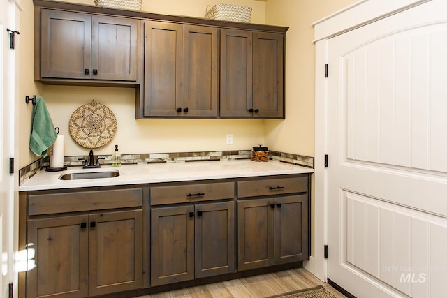 kitchen featuring sink, light wood-type flooring, and dark brown cabinets