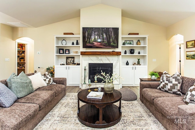 living room with light hardwood / wood-style flooring, vaulted ceiling, and a tile fireplace