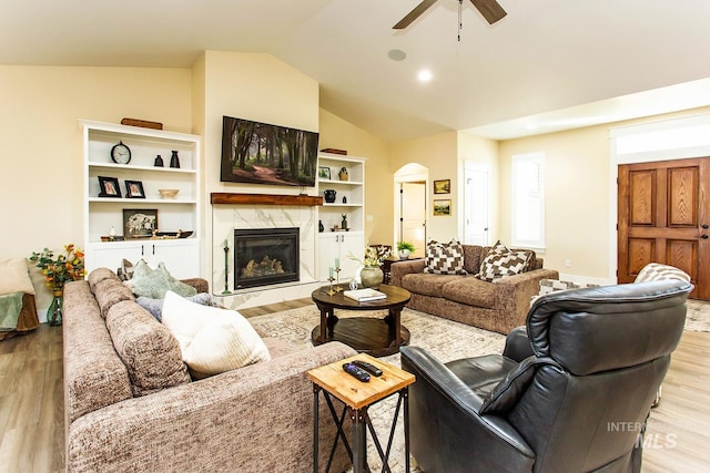 living room with lofted ceiling, a fireplace, ceiling fan, and light hardwood / wood-style floors