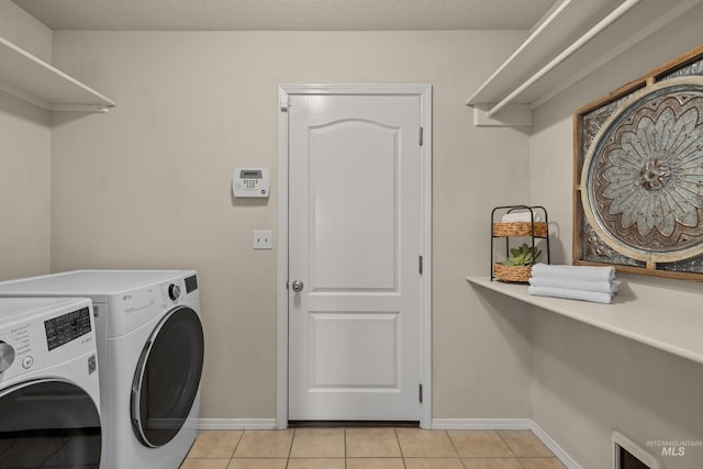 laundry area with light tile patterned floors, laundry area, baseboards, and washer and dryer