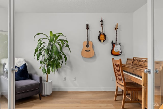 living area with a textured ceiling, wood finished floors, and baseboards