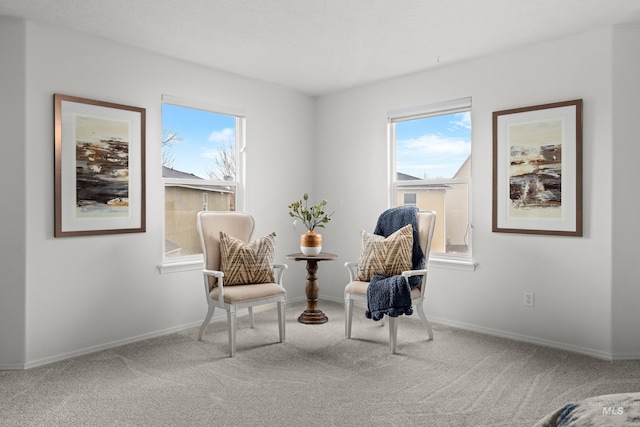 living area with baseboards, carpet flooring, and a healthy amount of sunlight