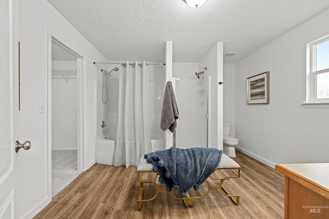 full bathroom with visible vents, toilet, wood finished floors, shower / bath combination with curtain, and a textured ceiling