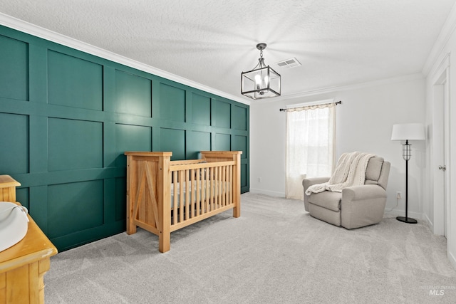 bedroom with a textured ceiling, a chandelier, a decorative wall, light carpet, and ornamental molding