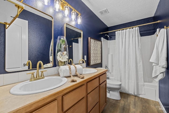 full bathroom with a textured ceiling, wood finished floors, a sink, and shower / bath combo with shower curtain