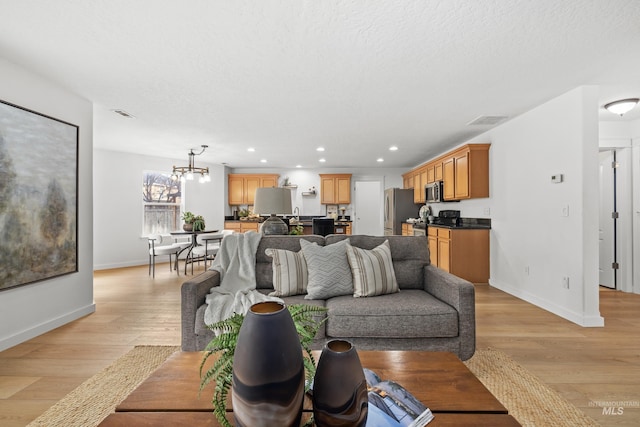 living area with visible vents, baseboards, a textured ceiling, light wood-style floors, and recessed lighting