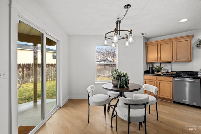 dining area featuring a notable chandelier, light wood finished floors, visible vents, a textured ceiling, and baseboards