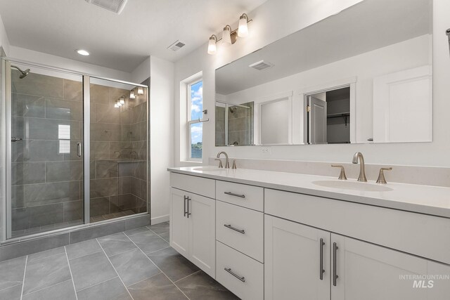full bathroom featuring tile patterned floors, a sink, a shower stall, and double vanity