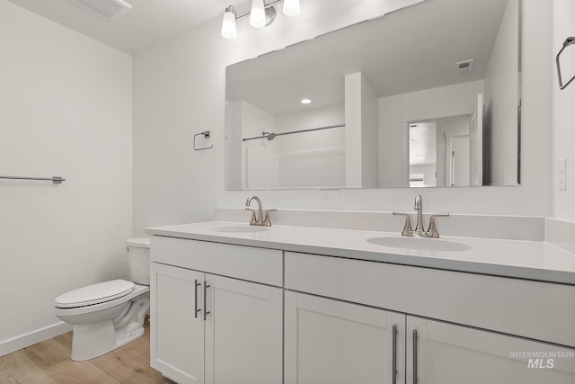 bathroom with wood finished floors, visible vents, toilet, and a sink