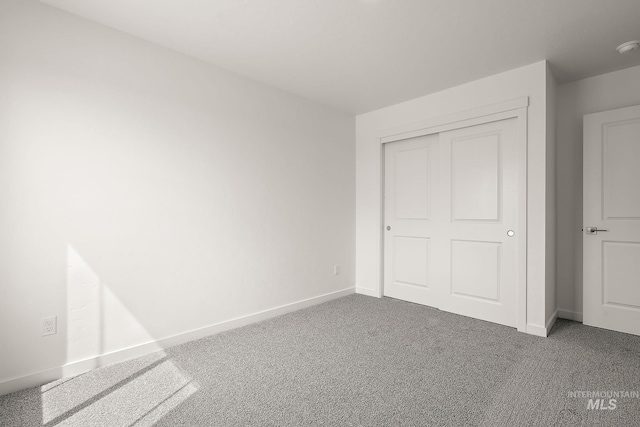 unfurnished bedroom with carpet floors, a closet, and baseboards