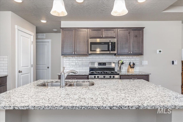 17719 Jackson Ridge Way, Nampa, ID 83687 - kitchen with stainless steel appliances, a sink, tasteful backsplash, dark brown cabinets, and light stone countertops
