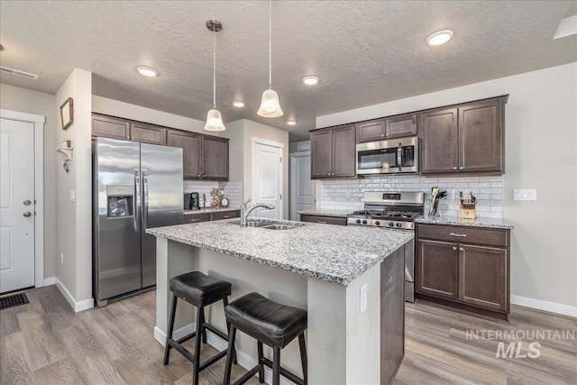 17719 Jackson Ridge Way, Nampa, ID 83687 - kitchen featuring appliances with stainless steel finishes, a sink, baseboards, dark brown cabinetry, and light wood finished floors